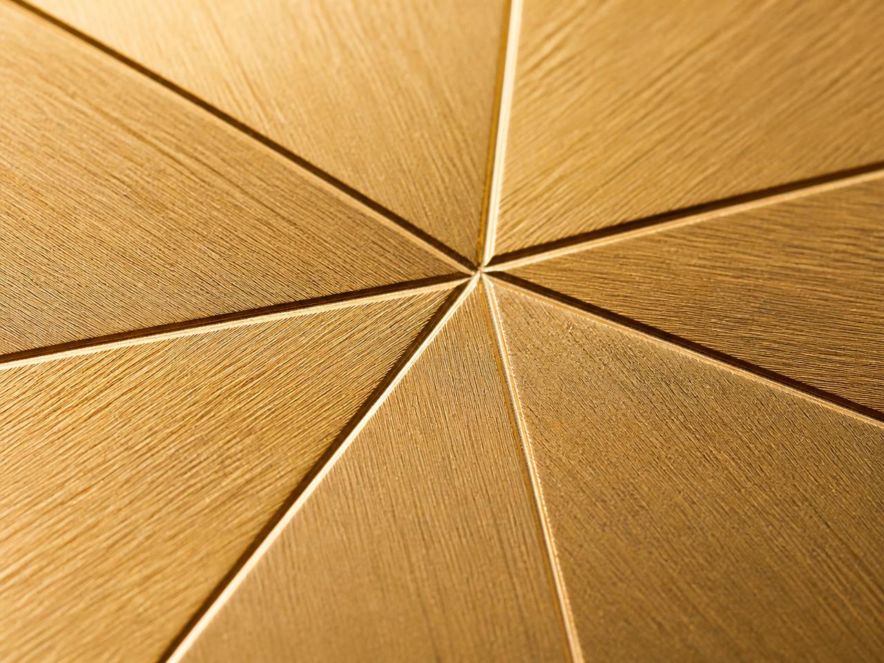 Macro detail of the Maple Edition surface — engraved angular vein facets across brushed champagne gold