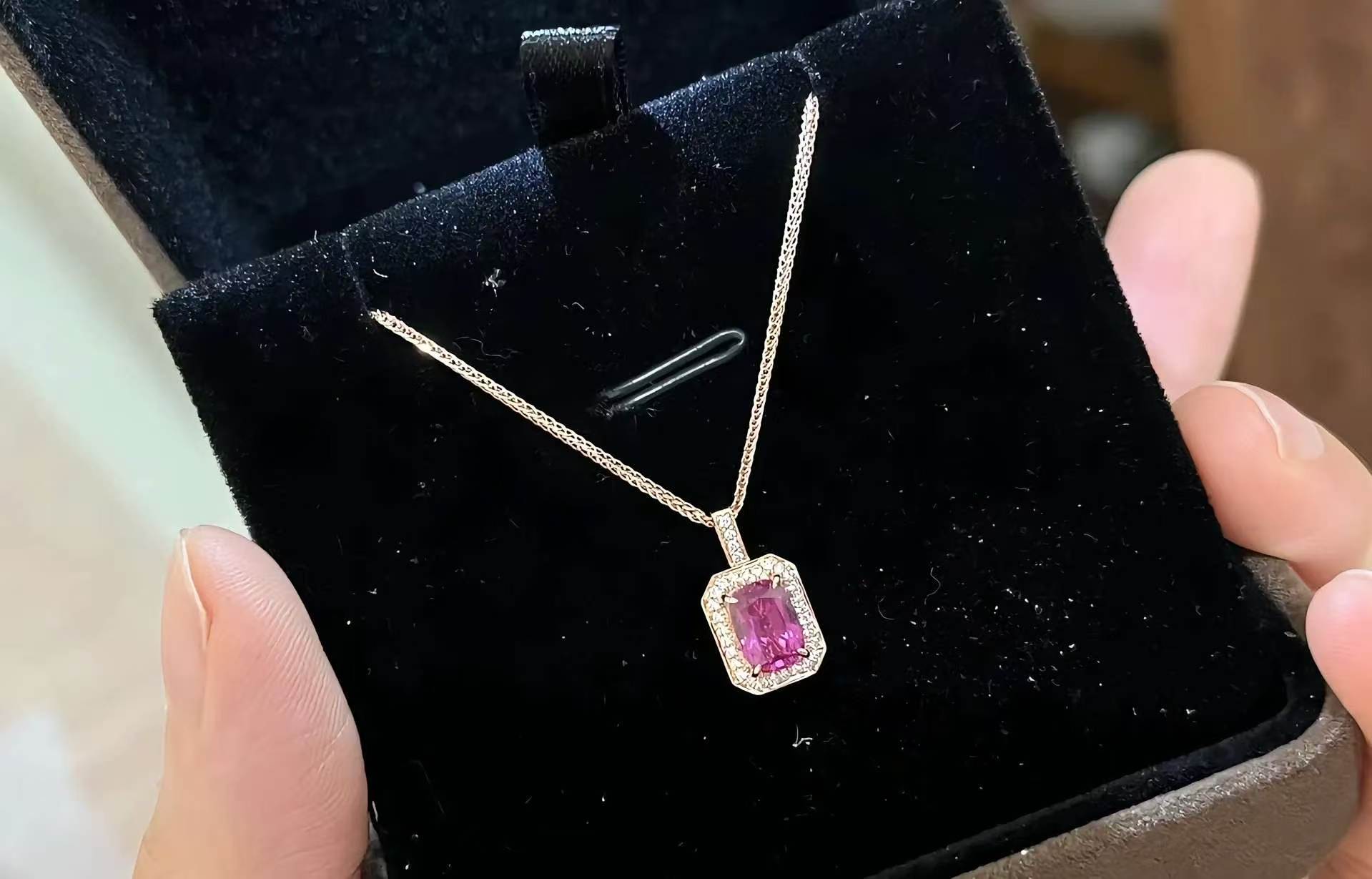 Radiant-cut pink sapphire pendant in a gold pavé halo held in a velvet box