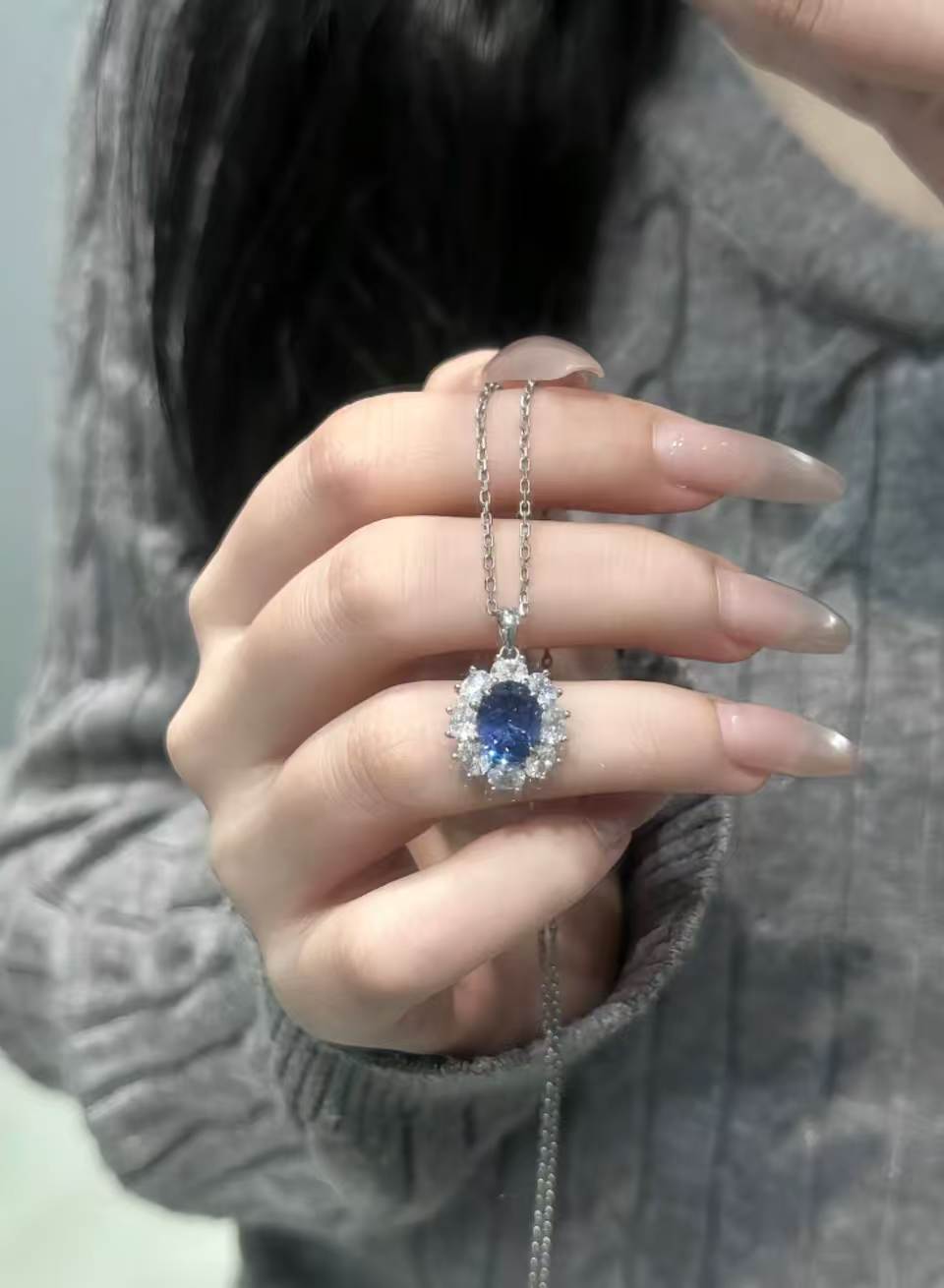 Halo pendant necklace held between fingertips